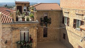 A courtyard with a tiled roof, brick buildings, and potted plants. - Camera famigliare un letto matrimoniale e 1 lettini (Corropoli)