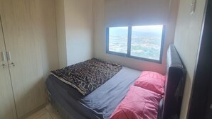 Une chambre à coucher avec un lit, une armoire et une fenêtre donnant sur la ville.