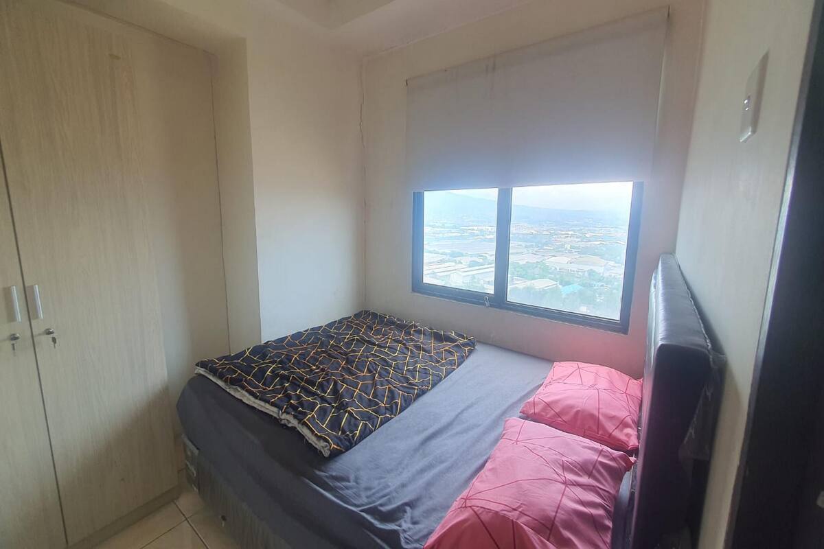 Une chambre à coucher avec un lit, une armoire et une fenêtre donnant sur la ville.