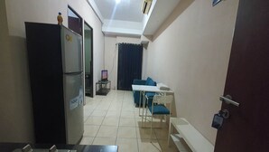Une cuisine compacte comprenant un réfrigérateur, une petite table avec des chaises et une porte donnant sur une autre pièce.