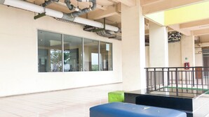 Un espace intérieur spacieux, doté d’une grande fenêtre, d’un banc noir et d’un tabouret vert.