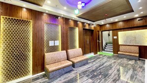 A modern lobby with wooden paneling, a seating area, and a staircase.