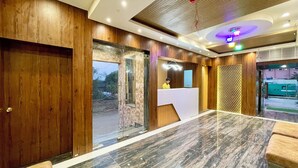 A reception area with a wooden reception desk, a glass partition, and a patterned wall.
