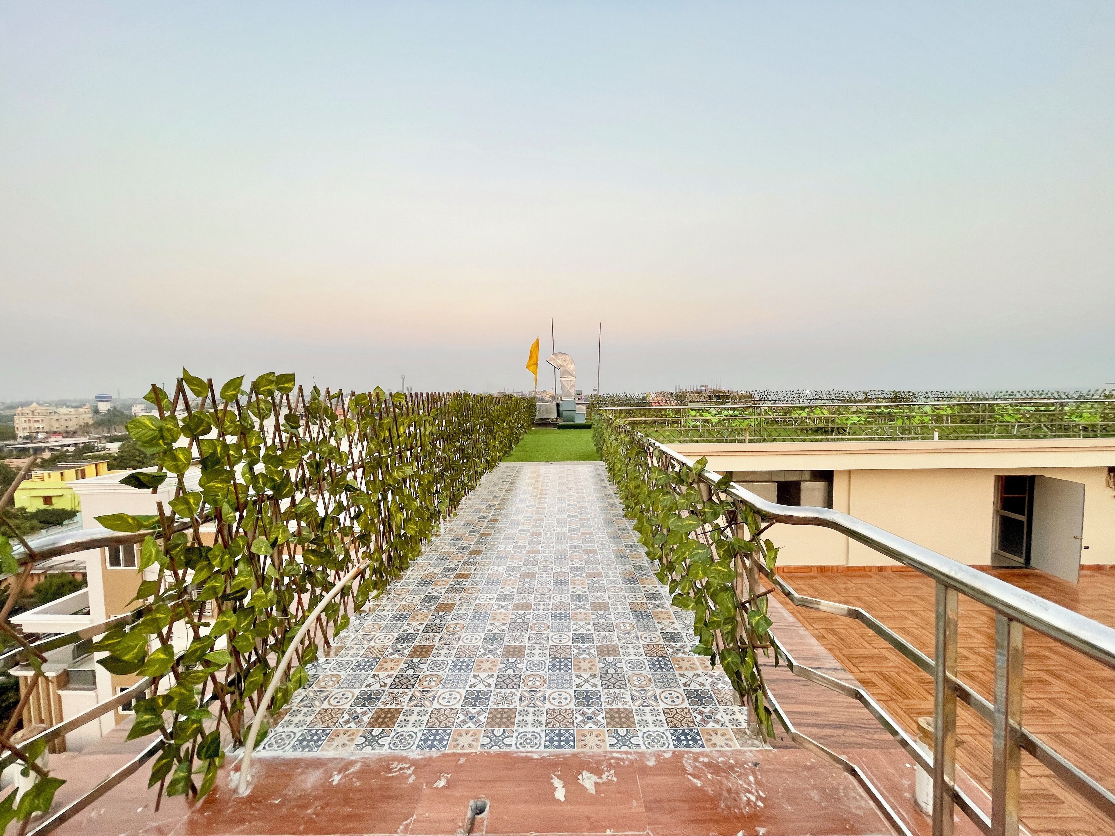 A tiled pathway leading to a building with a view of a cityscape.