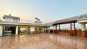A spacious outdoor area with a wooden floor, a covered seating area, and a view of the cityscape.