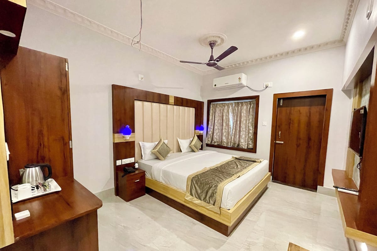 A hotel room with a bed, bedside table, nightstand, and a ceiling fan.