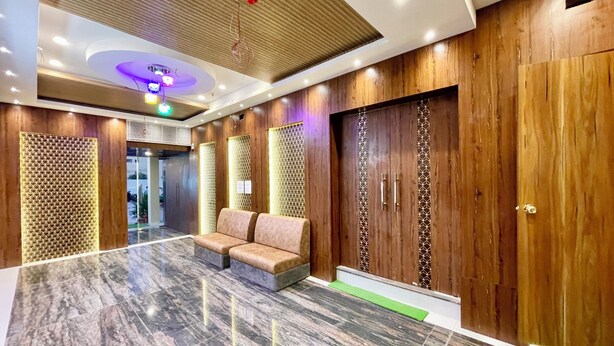 A lobby with a marble floor, wooden paneling, and a seating area.