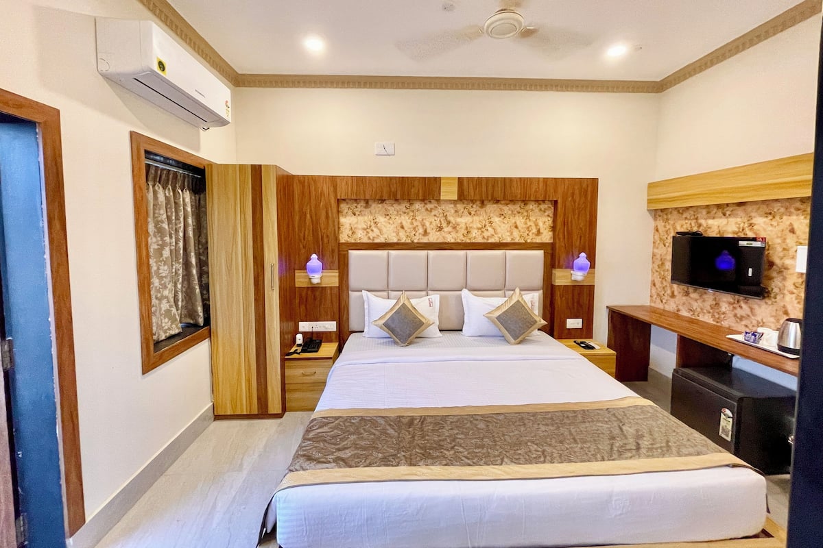 A hotel room with a large bed, a television, a desk, and a ceiling fan.