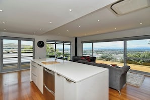 Cozinha moderna com uma ilha grande, amplas janelas com vista para a cidade e área de jantar com sofá.