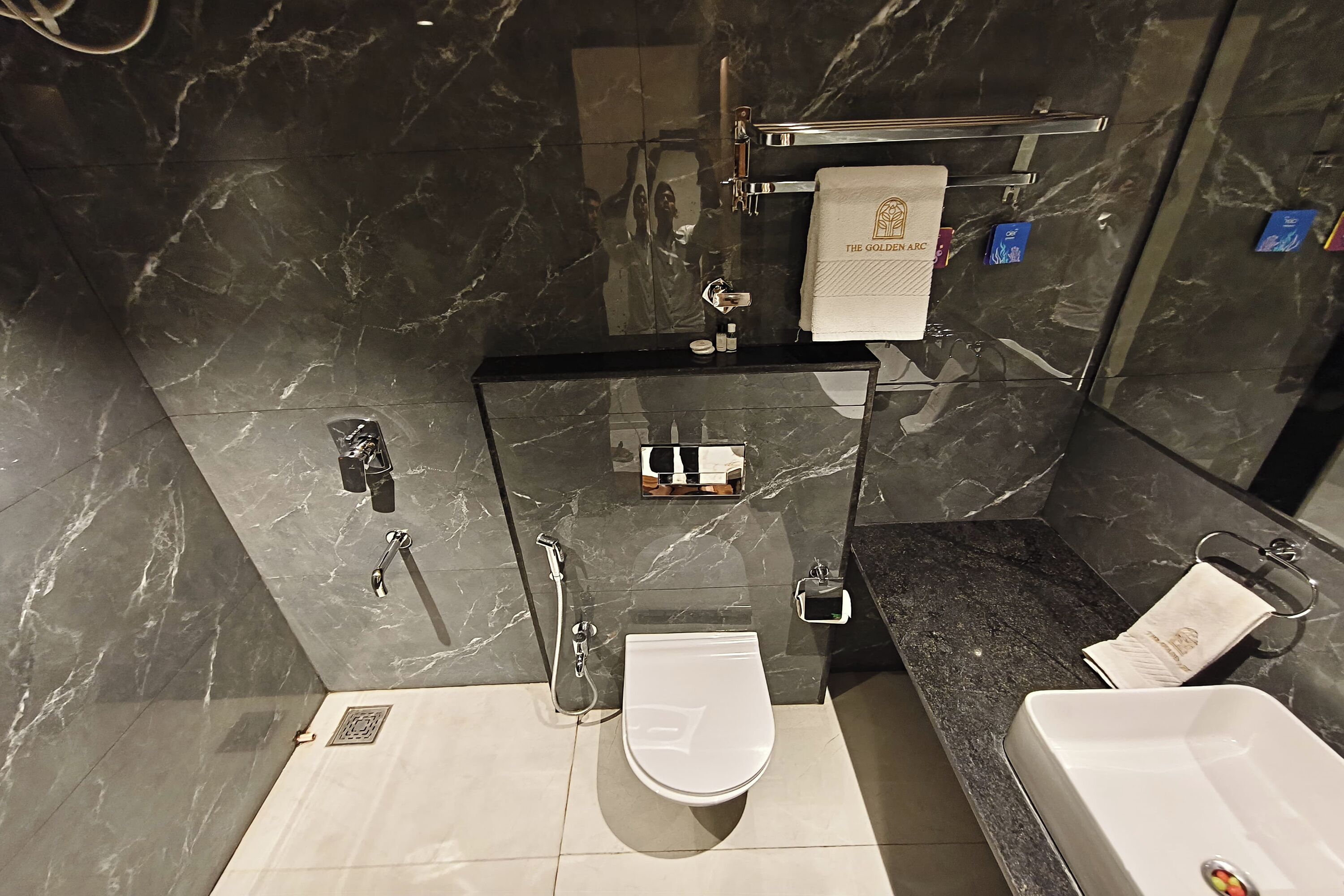 Une salle de bain moderne avec un sol en marbre, des toilettes, un lavabo et une douche.