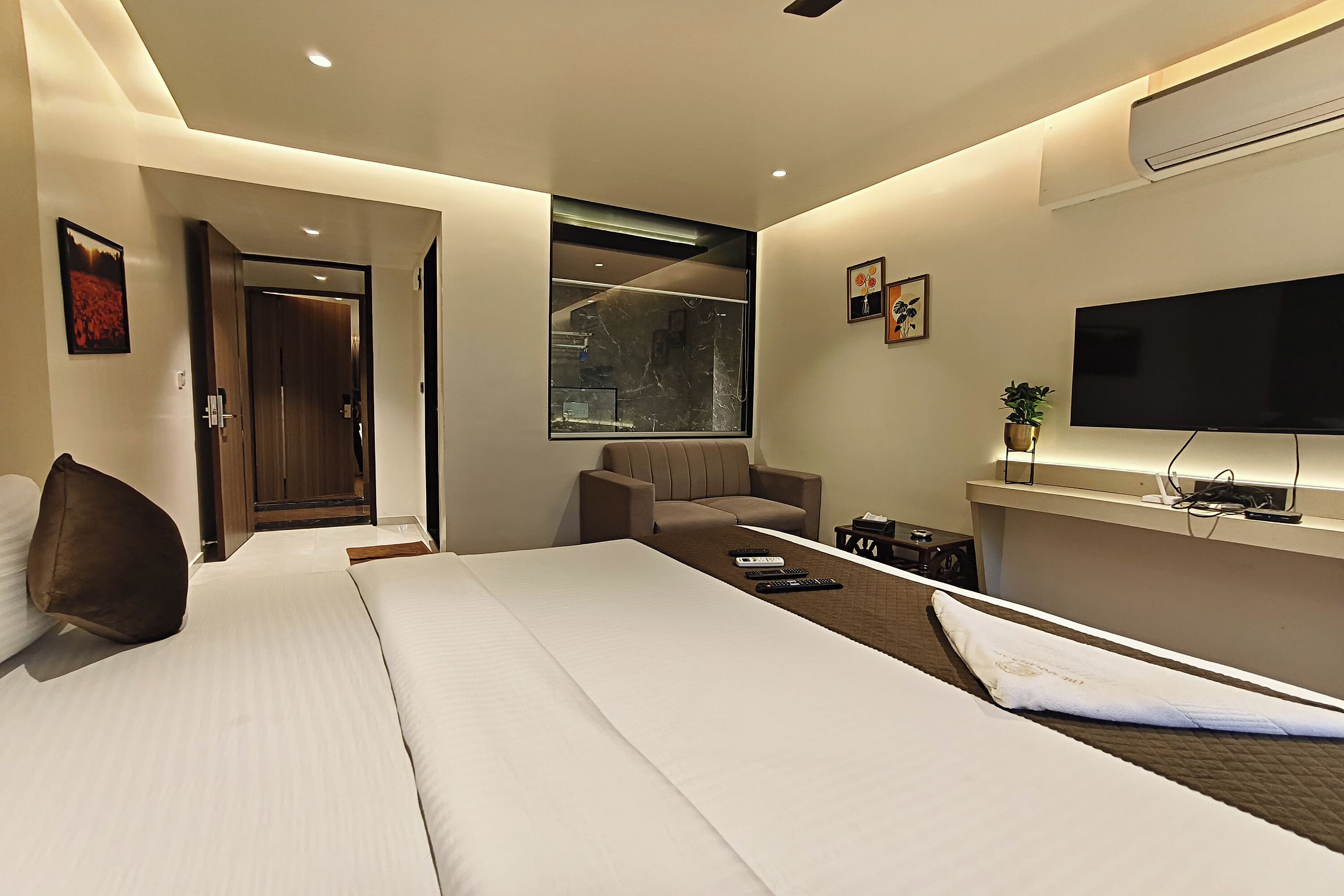 A modern hotel room with a large bed, a seating area with a chair, a TV, and a small table.