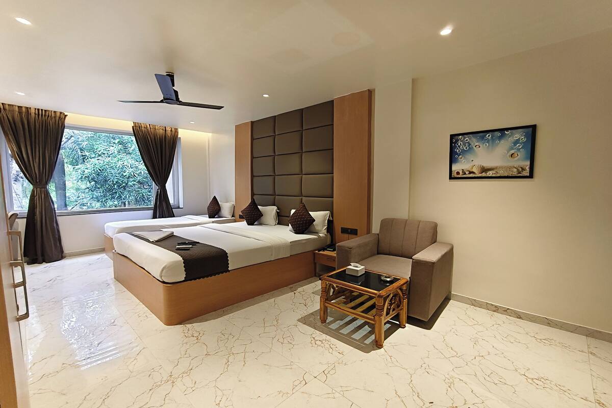 Quarto de hotel moderno com uma cama grande, um sofá, uma mesinha e um quadro na parede.