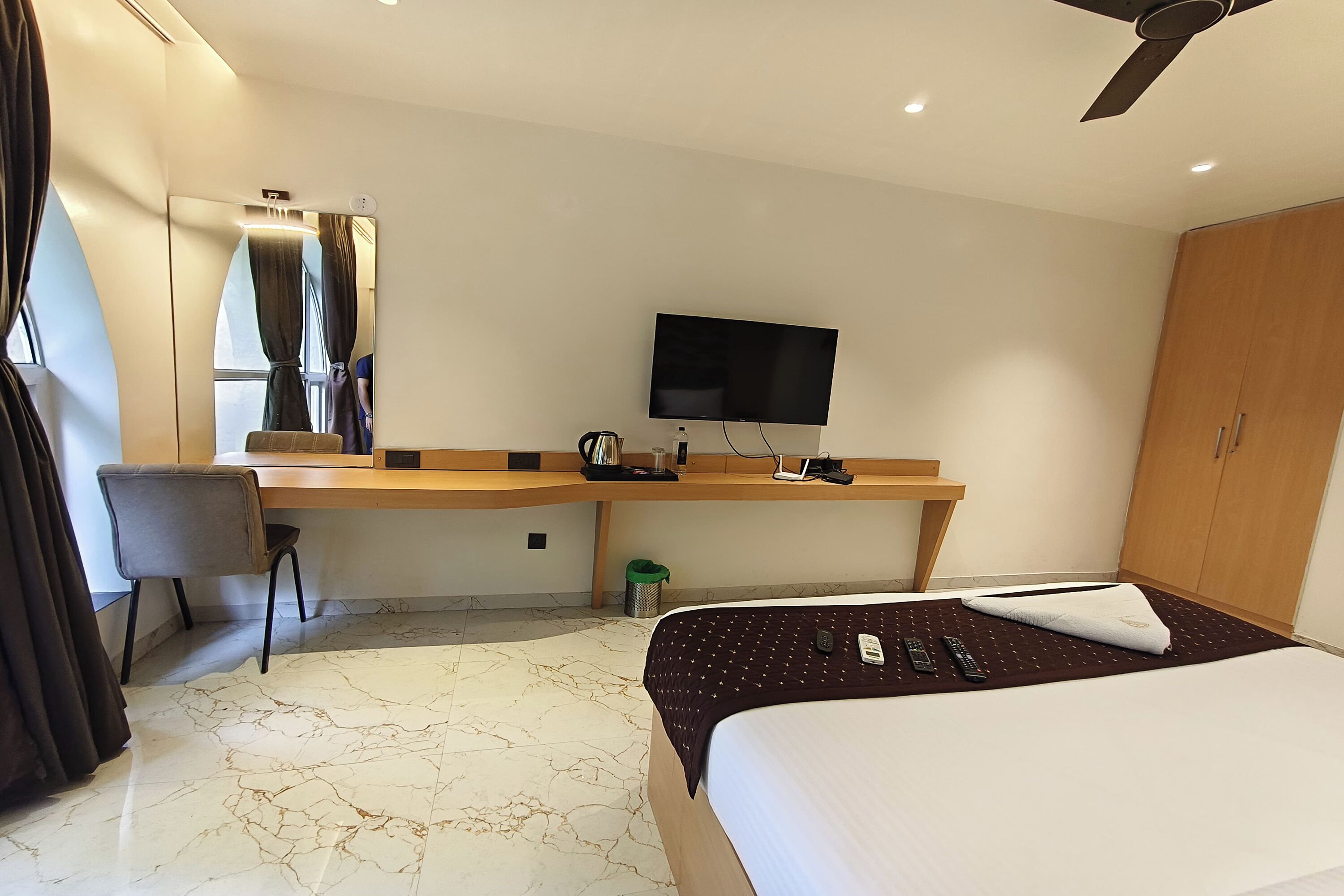 Una habitación de hotel con cama, escritorio, silla, televisor y armario.