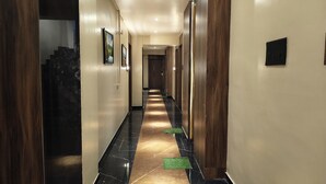 Ein Hotelkorridor mit Marmorboden, Holzvertäfelung und gerahmten Bildern an den Wänden.