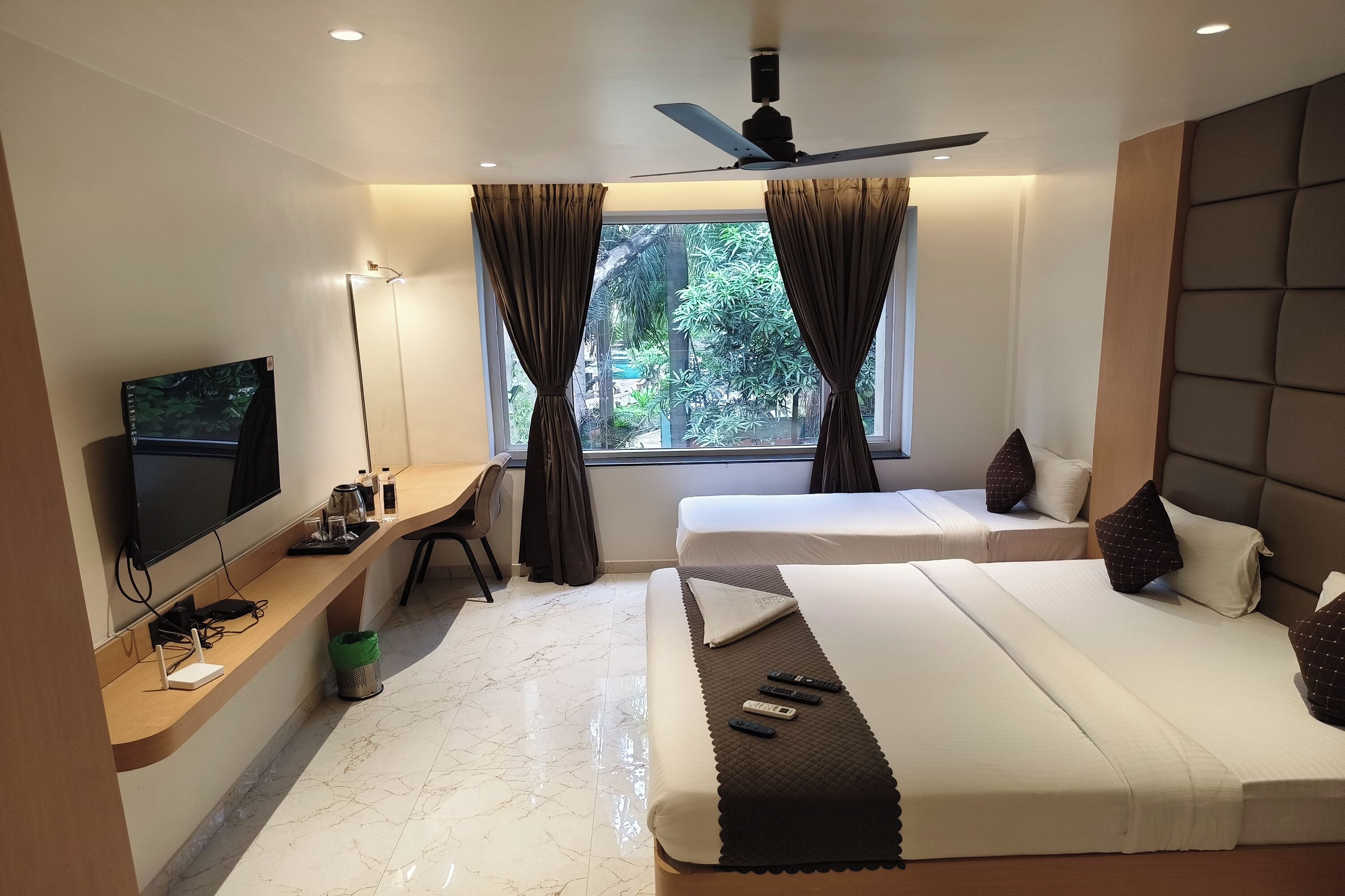 Una habitación de hotel con cama, escritorio y televisor, y vista a zonas verdes.