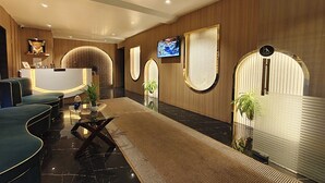 Eine moderne Hotelhalle mit Empfangstresen, Sitzgelegenheiten und dekorativen Elementen wie Pflanzen und Wandbildern.