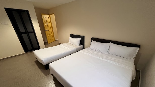 A room with two single beds, a wooden floor, a door, and a wall-mounted light fixture.