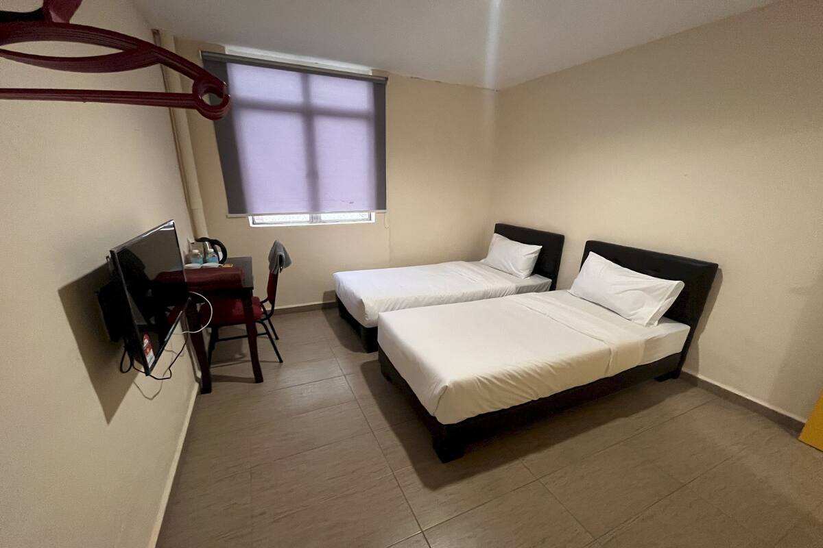 A room with two beds, a desk, and a chair.