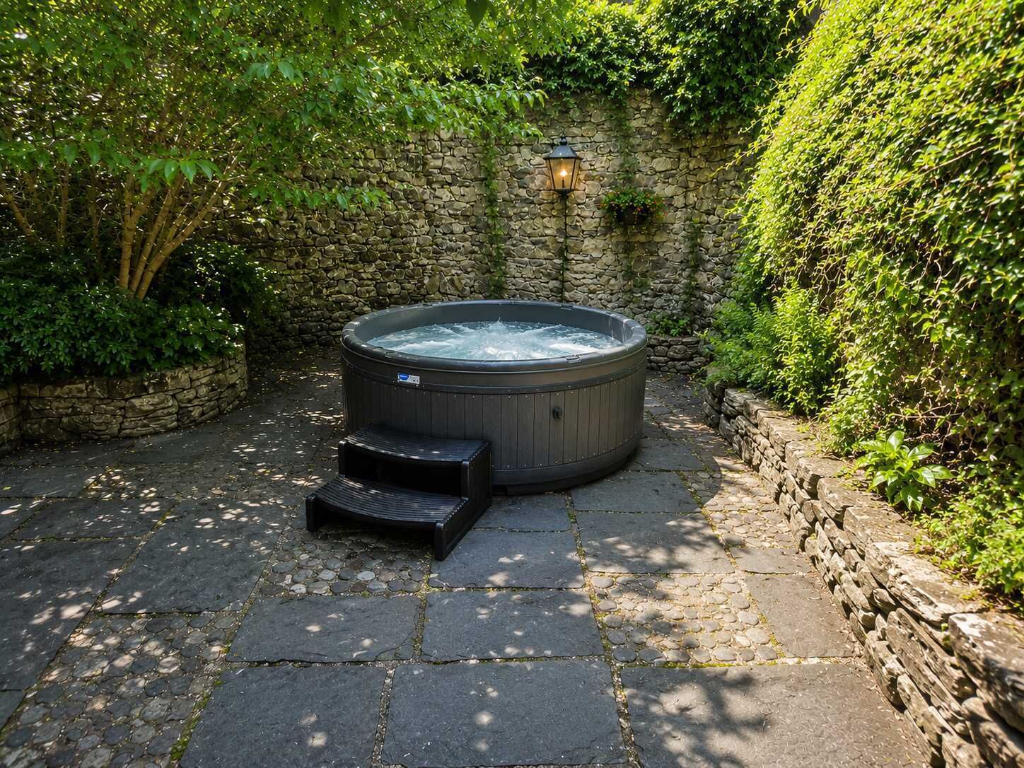 A hot tub in a garden with stone walls and steps leading to it.
