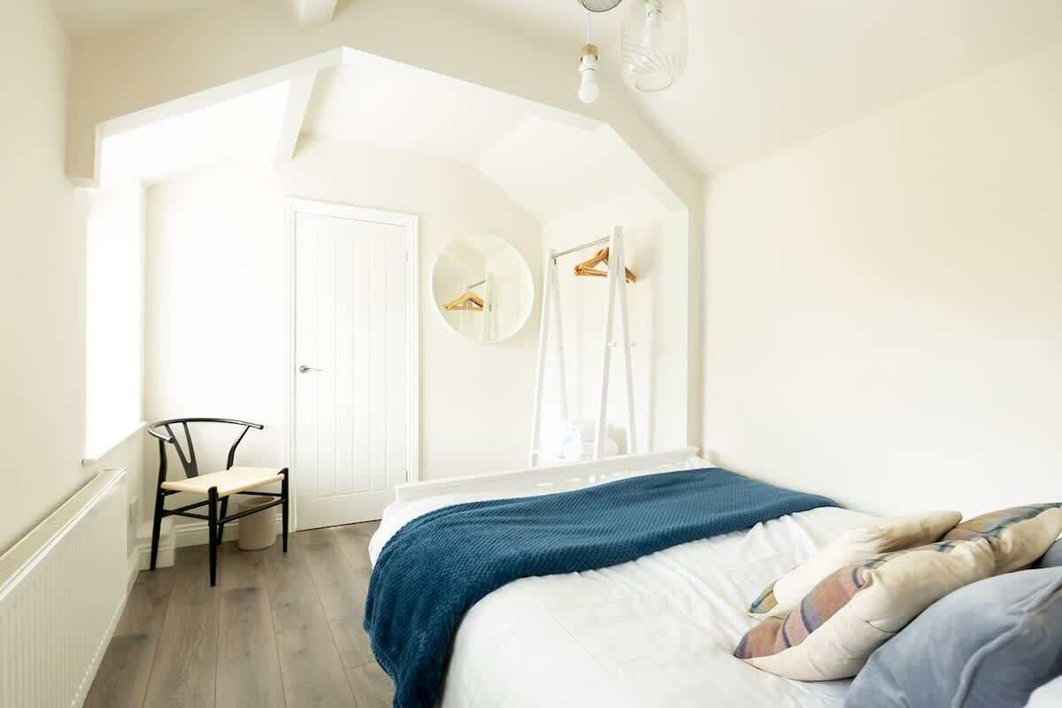 A bedroom with a bed, a chair, a wardrobe, and a mirror.