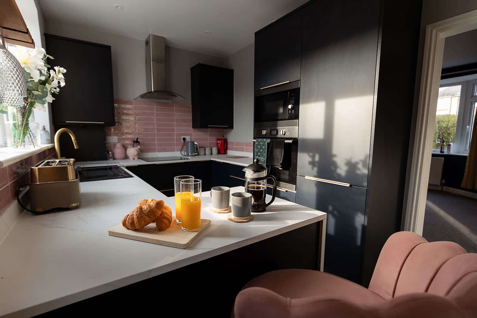 Cozinha moderna com ilha central, torradeira, cafeteira e um croissant.