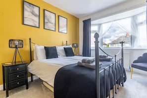 A bedroom with a bed, bedside tables, a window with curtains, and a view of the outside.