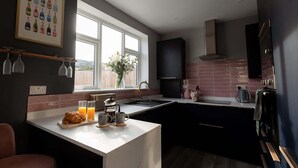 Eine moderne Küche mit einem großen Fenster, einer weißen Arbeitsplatte und einer dunkel gefliesten Rückwand.
