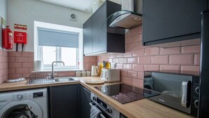 Una cucina compatta con lavatrice, forno a microonde e tostapane.