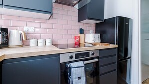 Una cucina compatta dal design moderno, completa di forno, microonde e frigorifero nero.