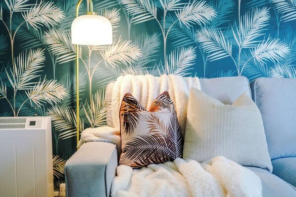 A cozy room with a patterned wallpaper, a white fluffy blanket, and a lamp.