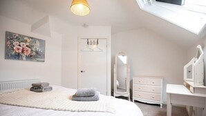 A bedroom with a bed, a dresser, a mirror, and a painting on the wall. - The Anchorage Apartments - No.6 (Conwy Principal Area)