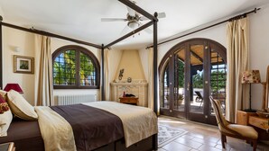 A bedroom with a large bed, a ceiling fan, a fireplace, and a view through arched windows. - 4015 Masseria Scilla by Barbarhouse (Carovigno)