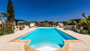 A rectangular swimming pool with a stone deck surrounding it, two pergolas with seating, and a clear blue sky. - 4015 Masseria Scilla by Barbarhouse (Carovigno)
