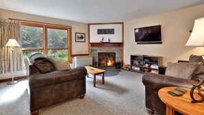 A cozy living room with a fireplace, leather sofas, a coffee table, and a television.