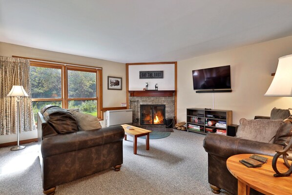 Una sala de estar acogedora con chimenea, sofás de cuero, una mesa de centro y un televisor.