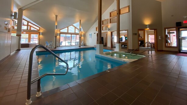 An indoor swimming pool with a clear view of the surrounding area, including a seating area and a staircase.