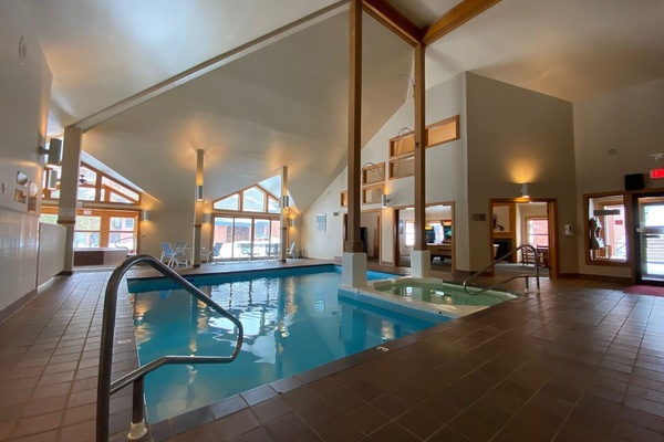 Trail Creek indoor pool room with tall windows, seating, and pool entry rail.