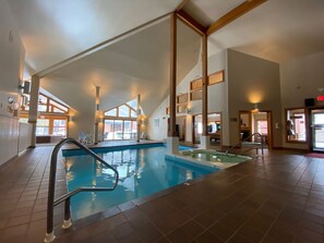 Una piscina interior con vistas despejadas del entorno circundante, que incluye un área de descanso y una escalera.