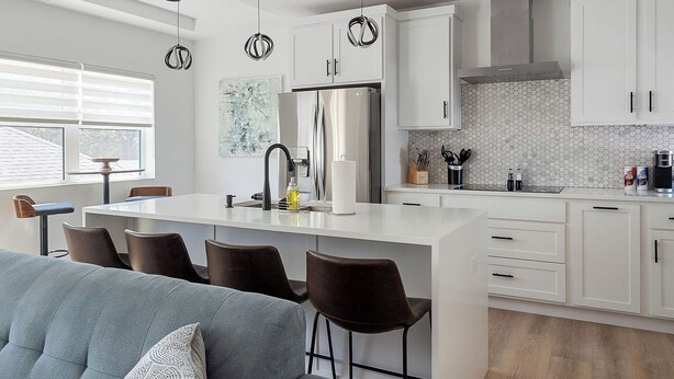 A modern kitchen with a central island, white cabinetry, and a hexagonal tile backsplash.