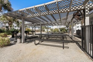 Enjoy dining or socializing in this shaded patio area with picnic tables and benches surrounded by lush greenery.