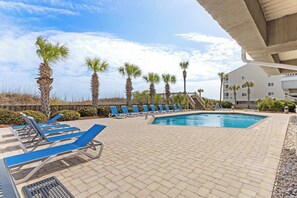 Relax by the pool surrounded by palm trees and lounge chairs.