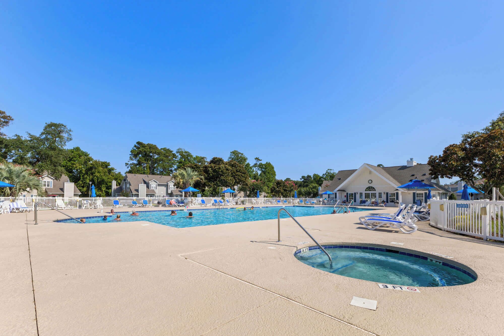 A pool area with multiple swimming pools, lounge chairs, and umbrellas.