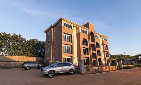 A multi-story residential building with a brick facade, multiple balconies, and a gated entrance.