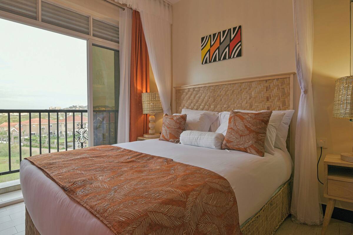 A hotel room with a large bed, a view of the city, and a balcony.