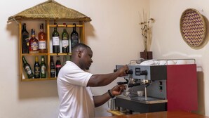 A barista preparing a drink at an espresso machine, with a shelf of various liquor bottles behind him. - Hotel 256 Kampala (Kampala)