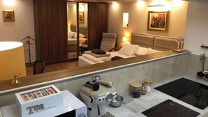 Une chambre d’hôtel dotée d’un grand miroir, d’un lit, d’un coin salon, d’une kitchenette et d’une salle de bain.