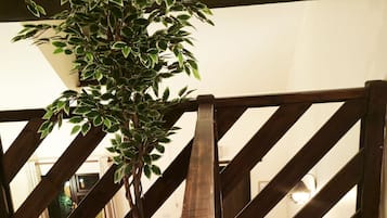 A staircase with a wooden railing, a plant, and a table with items on it.