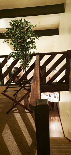 A staircase with a wooden railing, a plant, and a table with items on it. - Langford Apartments and Rooms (Bristol)