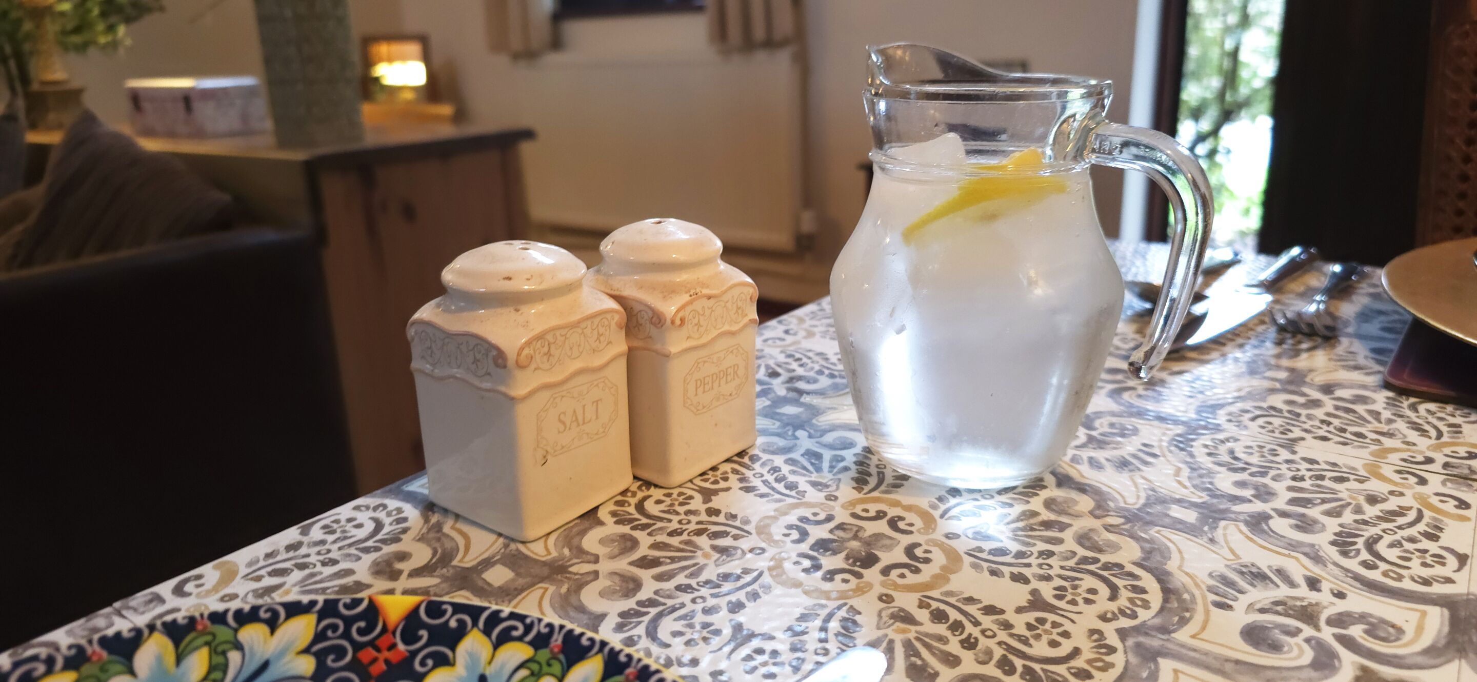 A table with a pitcher of water and two salt and pepper shakers.