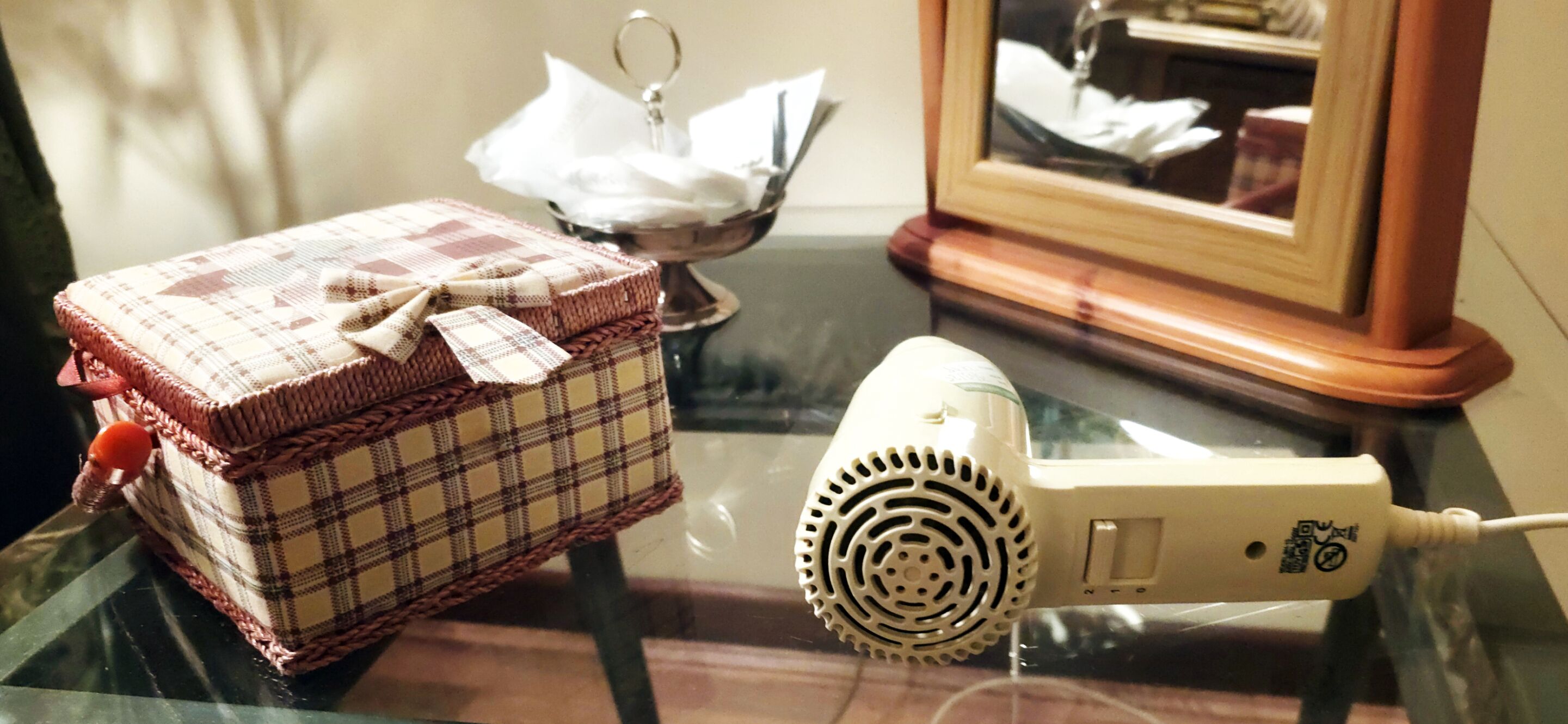 A checkered box with a bow, a hairdryer, and a framed picture on a table.